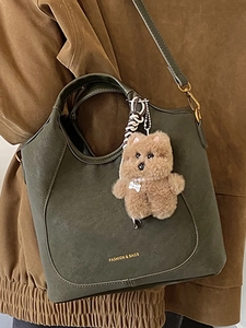 Deep olive green vintage bucket bag with plush bear charm and gold lettering details
