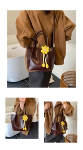Detail of dark brown leather bucket bag with top handles and floral charm accessory