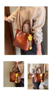 Detail view of large brown faux leather tote with floral charm and long shoulder strap