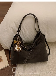 Détail d'un sac cabas marron avec breloque cœur léopard et bandoulière à œillets réglable