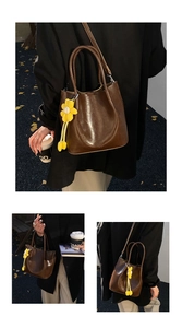 Detailed close-up of dark brown bucket bag with a yellow sunflower plush charm accessory
