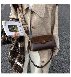 Detail of vintage brown crossbody bag featuring dual straps and suede leather texture