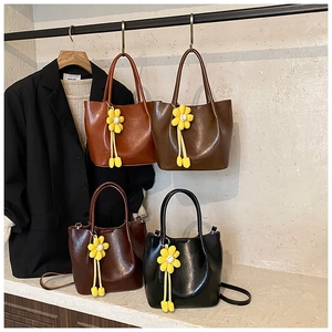 Detail of four colorful glossy PU leather bucket bags with cute sunflower pendants