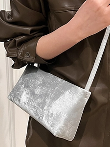 Minimalist silver underarm bag with metallic foil texture and a slim shoulder strap