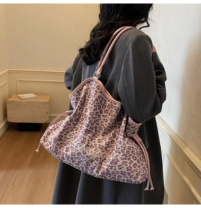 Detail of leopard print tote bag with pink drawstring and Lucky embroidery on dark grey coat