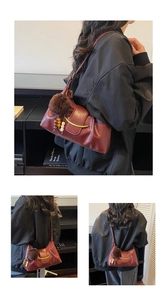 Detail of burgundy leather shoulder bag with gold metal trim and fuzzy tassel accessory