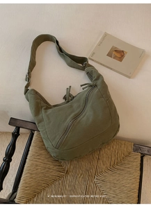 Detailed macro view of dark green canvas hobo bag with multiple zippers and adjustable strap