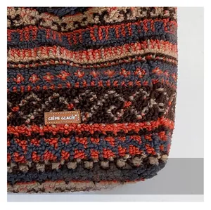 Gros plan sur le tissu moutonné multicolore et l'écusson en cuir du sac cabas