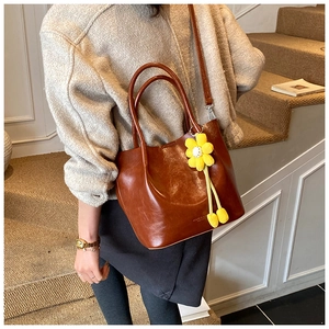 Detailed close-up of dark brown leather tote bag texture with yellow floral bag charm