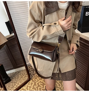 Detail of dark brown leather crossbody bag with vintage bronze hardware and jacquard strap