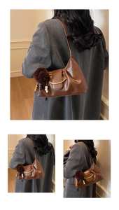 Detail view of brown vintage dumpling bag with golden metal trim and plush pendant