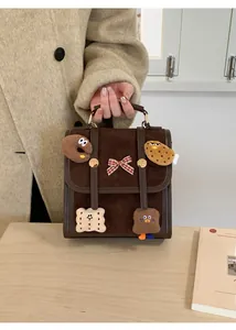 Detail of a brown matte backpack with cute cartoon cookie patches and a red plaid bow