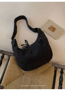 Detail shot of black canvas hobo bag with tassel zipper on a vintage armchair