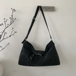 Detail of a large black suede tote bag featuring a decorative silver metal eyelet belt strap