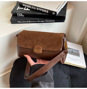 Detail of dark brown tote bag with suede texture and gold buckle on a stylish background
