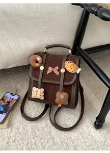 Detail of dark brown faux suede backpack featuring cute plush cookie charms and bow accessory