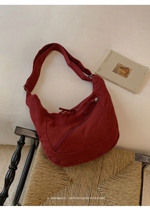Detail of burgundy hobo bag showing canvas material and adjustable wide strap