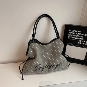 Detail of grey star-print tote bag with black leather straps and drawstring closure