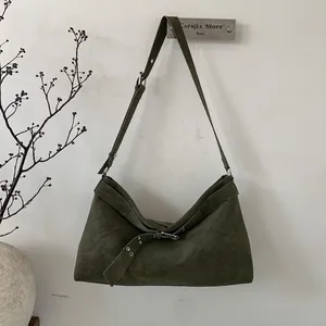 Detail view of olive green suede shoulder bag with metal eyelets and decorative buckle strap