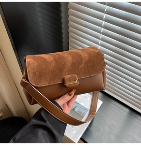 Detail of brown contrast leather handbag with suede flap and gold metal magnetic buckle