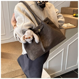 Detail of dark grey-brown tote bag with white stitching and plush bunny pendant