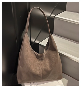Detail of coffee brown suede hobo bag showing minimalist stitching and wide shoulder strap