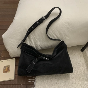 Macro shot of matte black suede tote bag with adjustable shoulder strap and metal buckle