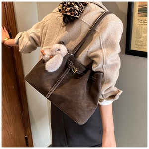 Detail of brown suede tote bag with white contrast stitching and gold buckle