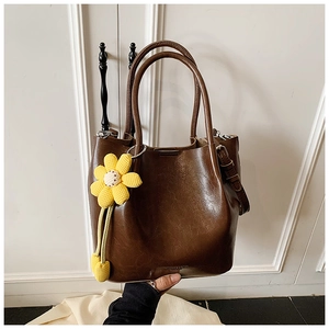 Detail of a brown leather bucket bag with a handcrafted crochet sunflower charm