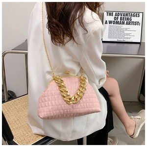 Pink pleated shell bag with chunky gold chain strap shown in a lifestyle fashion setting