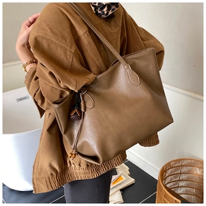 Detailed view of brown PU leather tote bag with vintage tassel and wooden bead charm
