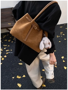 Brown frosted leather tote bag with white rabbit pendant in autumn street setting