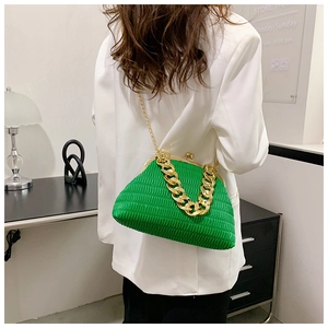 Detail view of bright green ruched dumpling bag with gold chain straps on white suit