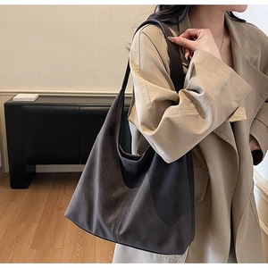 Detail of dark brown tote bag in matte leather worn with a trench coat for winter style
