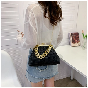 Detail of black pleated shell bag with chunky gold chain handle and slim shoulder strap