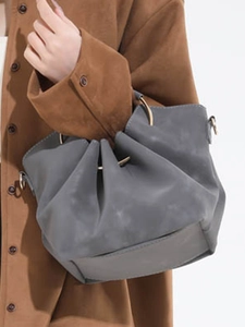 Sac nuage plissé gris foncé avec anneaux dorés porté à l'épaule de manière élégante