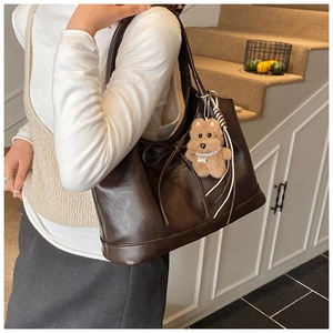 Deep brown matte leather tote bag with a bow drawstring and a cute plush dog pendant