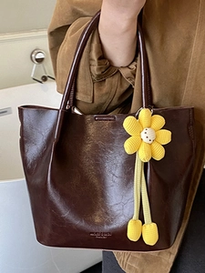 Minimalist dark brown glossy tote bag with a yellow hand-woven flower charm decoration
