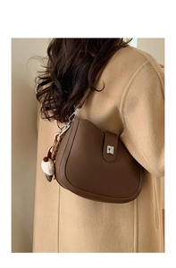 Detail view of dark brown pebbled leather bucket bag with ice cream pompom on winter coat