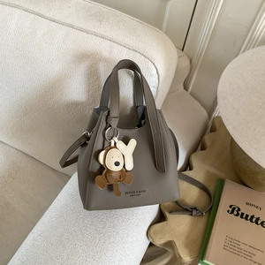 Dettaglio della borsa a secchiello in pelle taupe con manici su un divano elegante