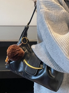 Large black pleated hobo bag with gold moon hardware and plush ball charm accessory