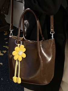 Minimalist dark brown glossy leather tote bag with a yellow sunflower charm for winter style
