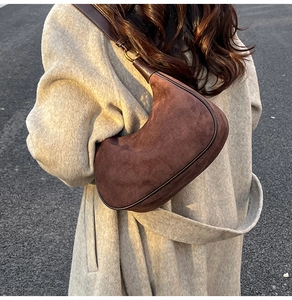 Detail of dark brown suede hobo bag with adjustable shoulder strap on a model