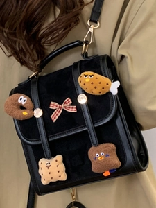 Minimalist black leather backpack with cute plush food charms and red bow detail