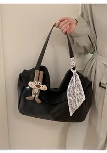 Detail of black suede tote bag with printed silk scarf and cute rabbit charm pendant