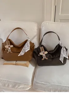 Brown and coffee suede tote bags with rabbit charm and scarf on a white sofa