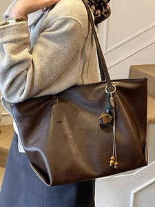 Retro dark brown large tote bag with tassel charm worn over shoulder for daily commute