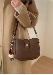 Detail of dark brown pebble leather shoulder bag with silver buckle and plush charm