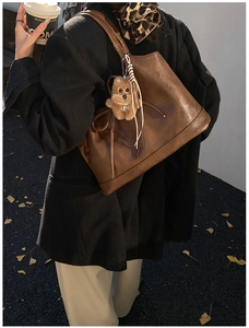 Large dark brown leather tote bag with bow detail and bear charm in autumn street style
