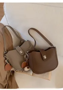 Detail of gray and brown litchi pattern leather bucket bags with heart tags and plush charms
